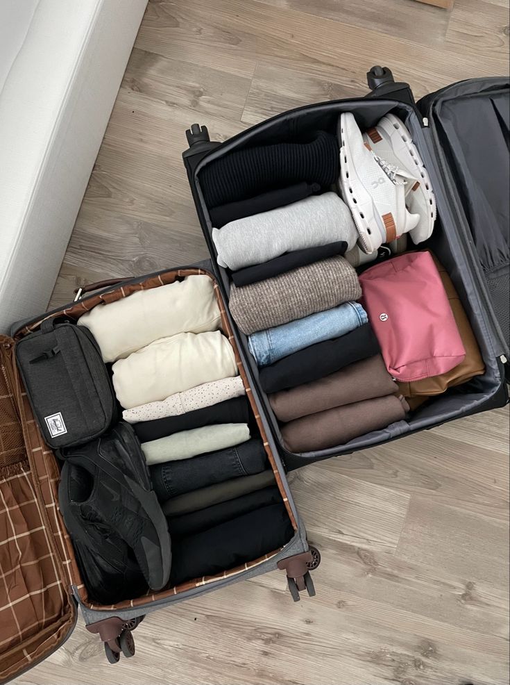 Neatly organized open suitcase with folded neutral clothes and shoes arranged aesthetically.