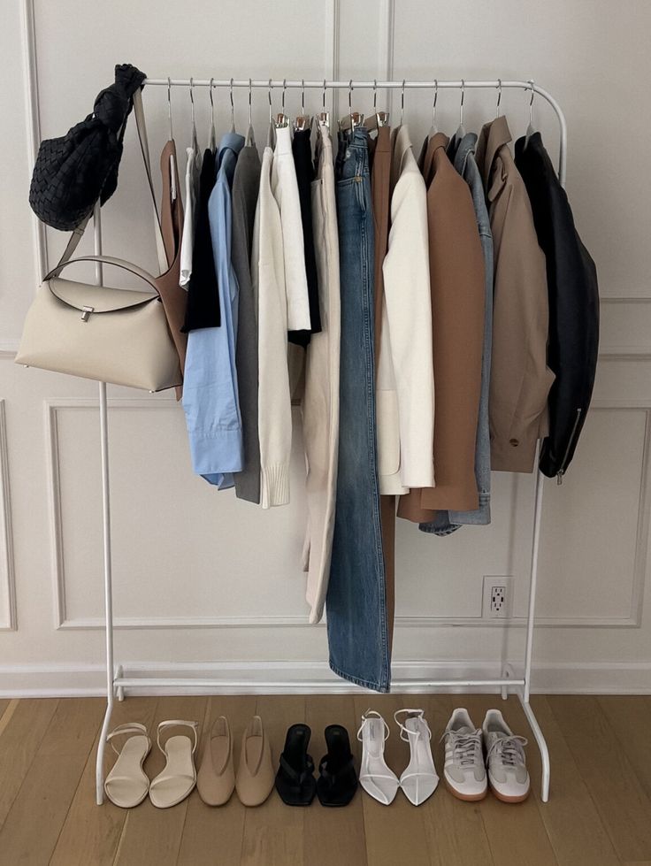 Minimalist clothing rack with neutral-toned wardrobe staples, shoes, and handbags.