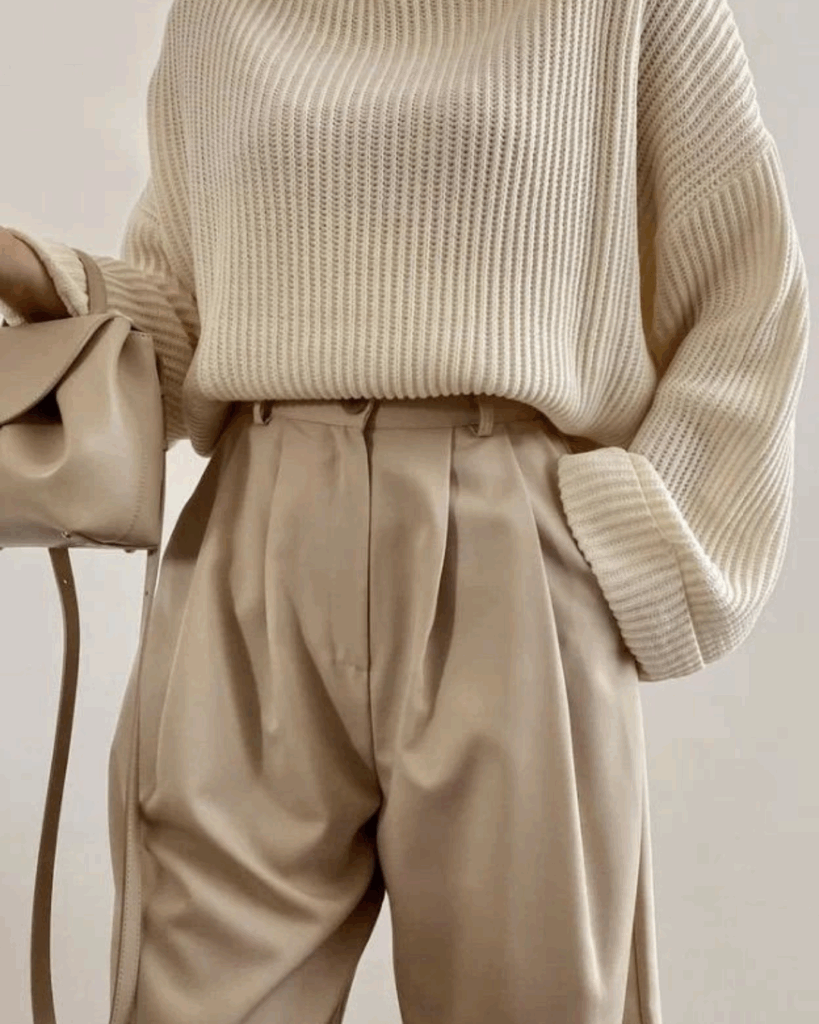 Neutral-toned outfit with beige tailored trousers and cream knit sweater, showing a modern structured look that avoids frumpy, shapeless styling.