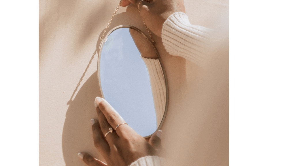 Close-up of a woman's hand touching a mirror, symbolizing self-reflection and personal style awareness.