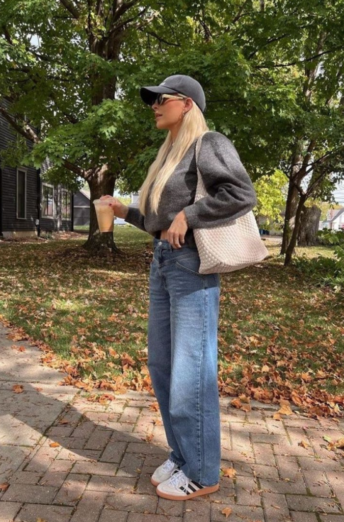 Woman wearing straight leg jeans, a knit top, and a cap while walking outdoors