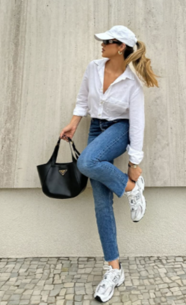 Woman wearing white sneakers, blue jeans, white shirt and cap styled for a casual summer day.